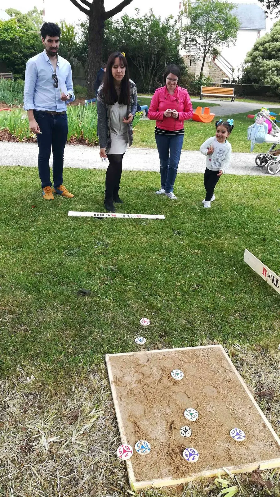 Famille jouant au Roll Kubb sur l'herbe dans un parc