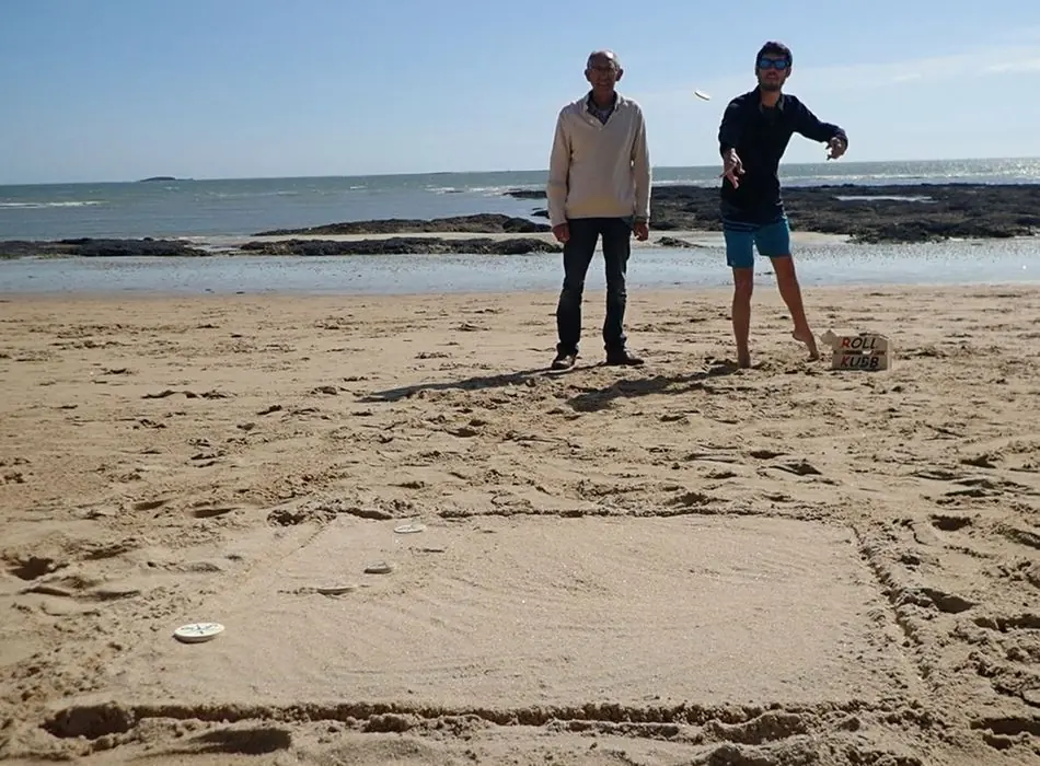 Deux joueurs lançant leurs Kubbs sur une plage