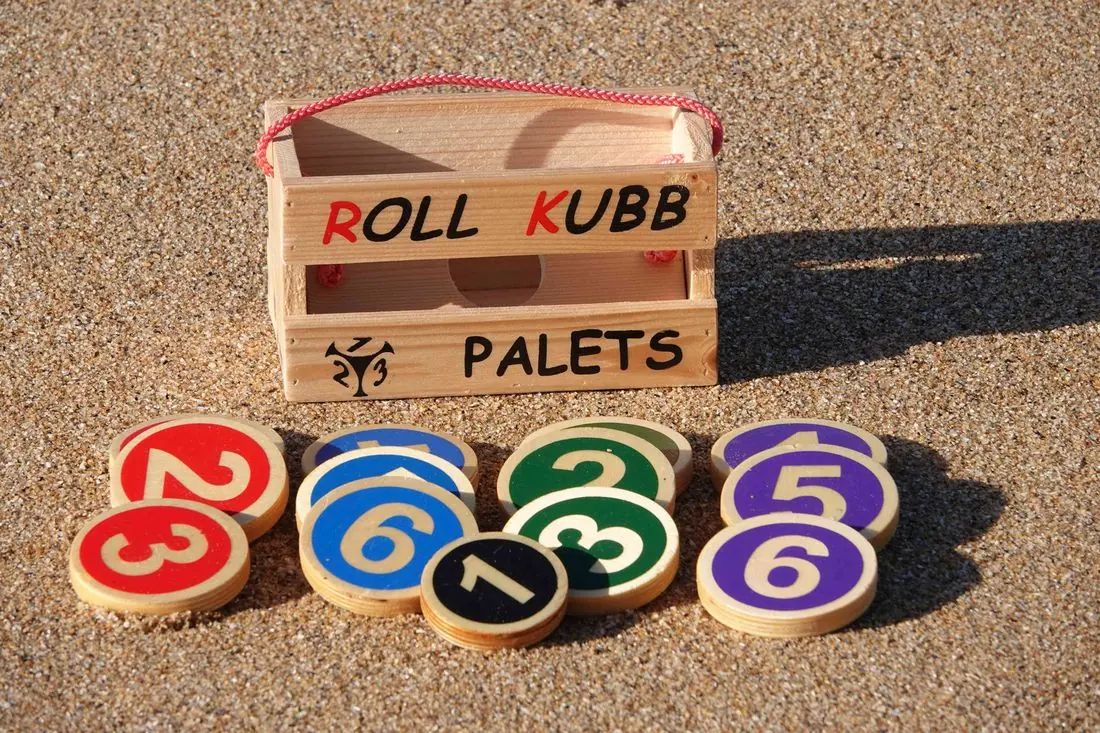 Caisse Roll Kubb Palets et ses palets en bois numérotés posés sur le sable